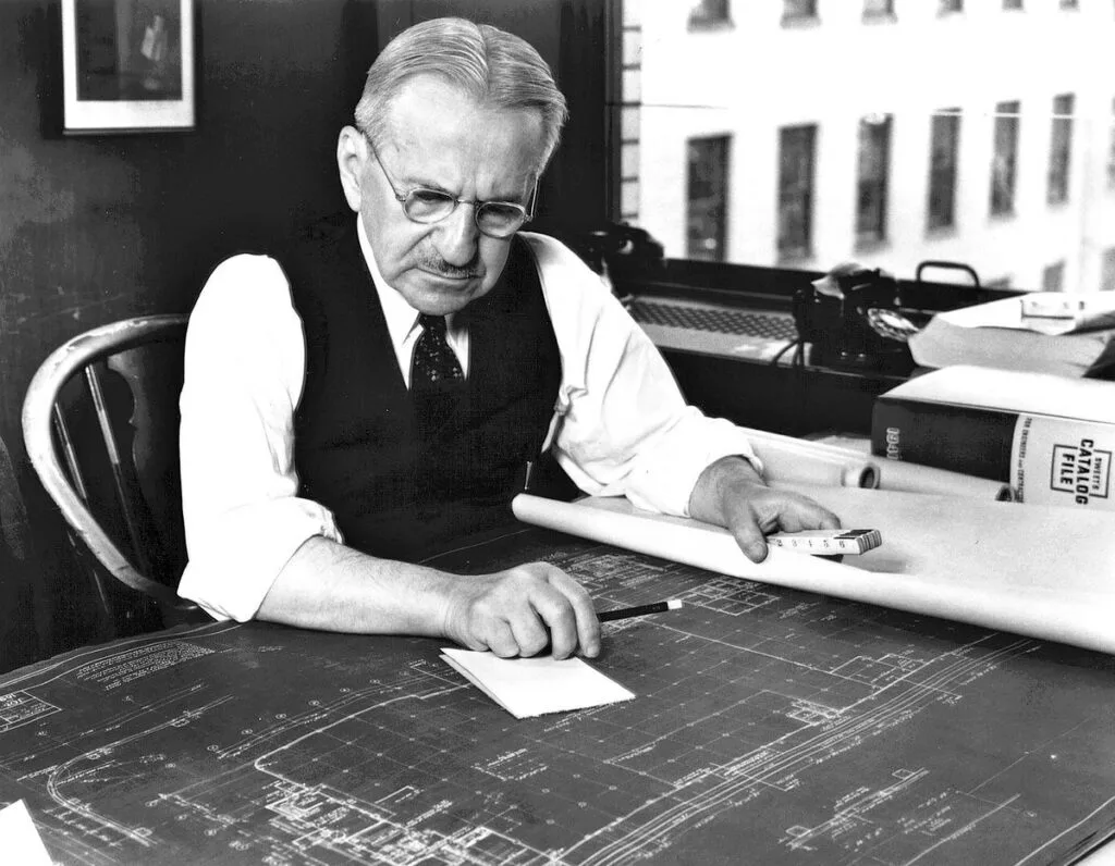 El arquitecto Albert Kahn revisando los planos de una planta industrial sobre su tablero de dibujo