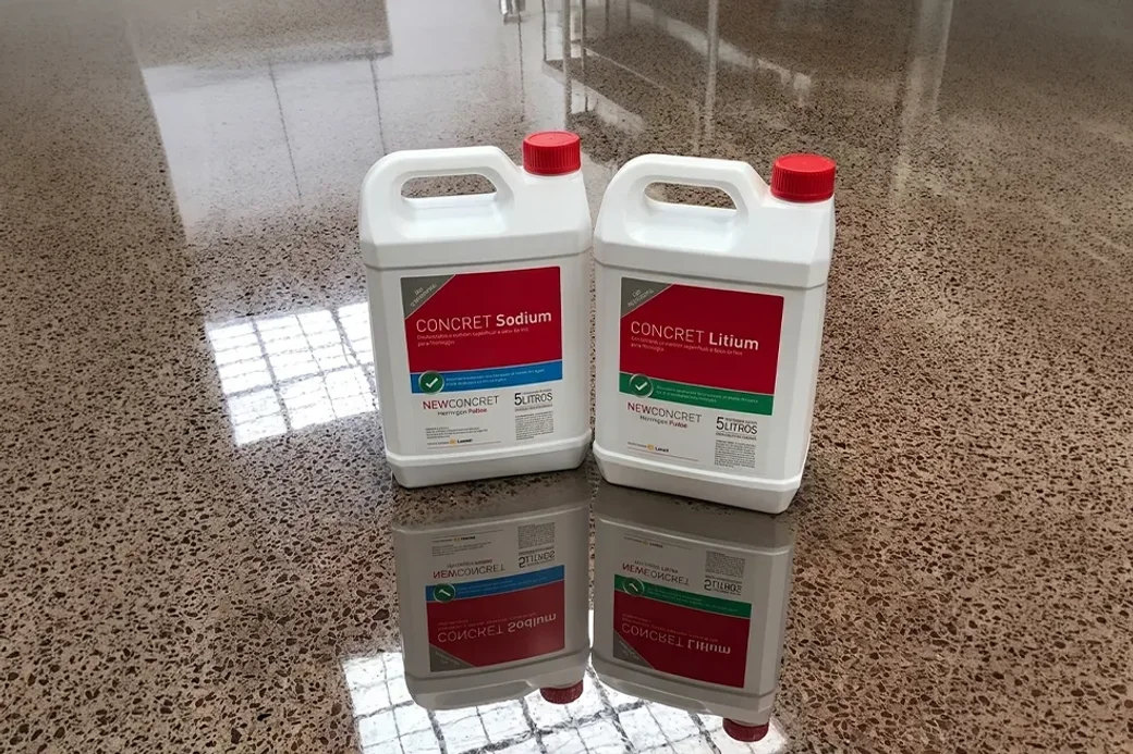 Bidones de Concret Sodium y Concret Litium apoyados sobre un piso de hormigón pulido que refleja la nave