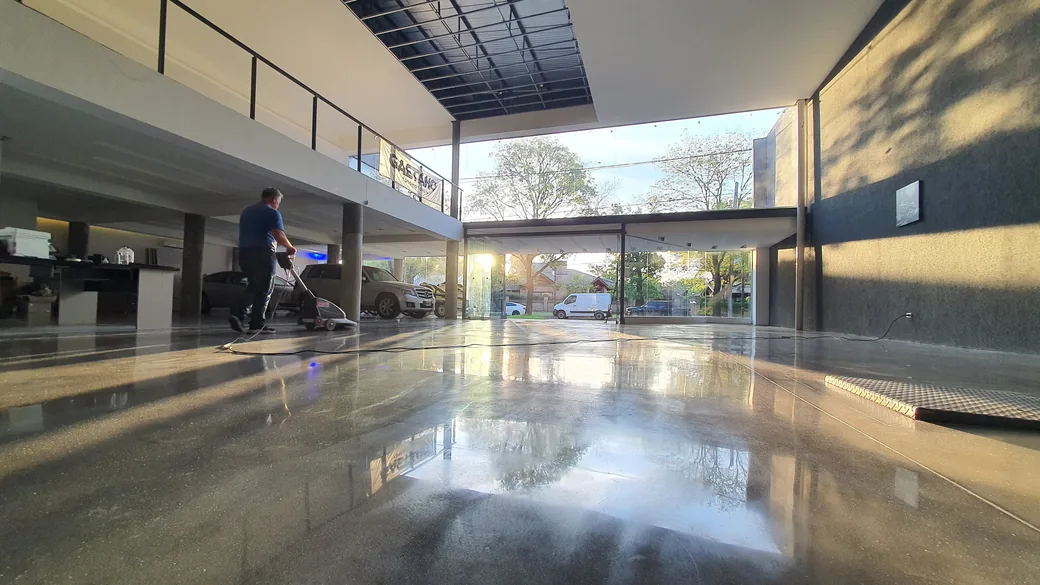 Showroom de autos con piso de hormigón pulido a espejo que refleja la fachada vidriada y los vehículos