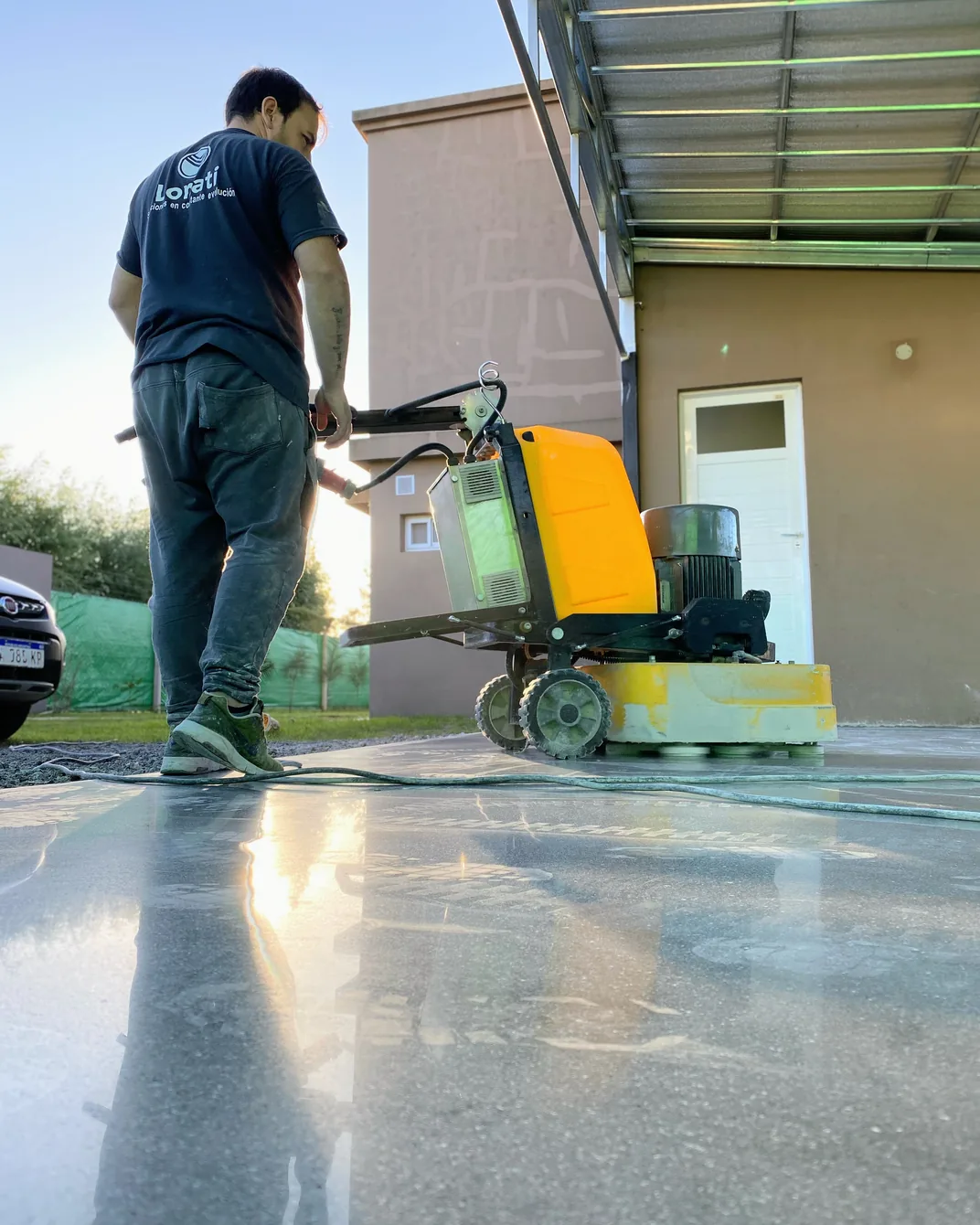 Operario puliendo con una pulidora el piso de hormigón de una galería en una vivienda