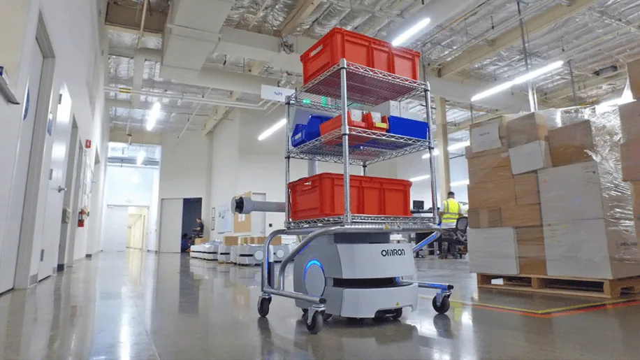Robot móvil autónomo transportando un carro con insumos sobre un piso de hormigón pulido